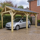 A wooden gazebo carport with a dark grey shingle roof is shown in a UK garden setting, sheltering a silver hatchback car on a gravel driveway next to a brick house.