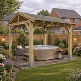 A wooden gazebo with a grey shingle roof over a hot tub on a paved patio in a landscaped UK garden.