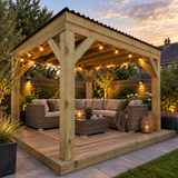 A large wooden garden pergola with black roof, integrated string lights, supporting an outdoor patio set with wicker sofas, a coffee table, and a rug in a landscaped backyard at dusk.